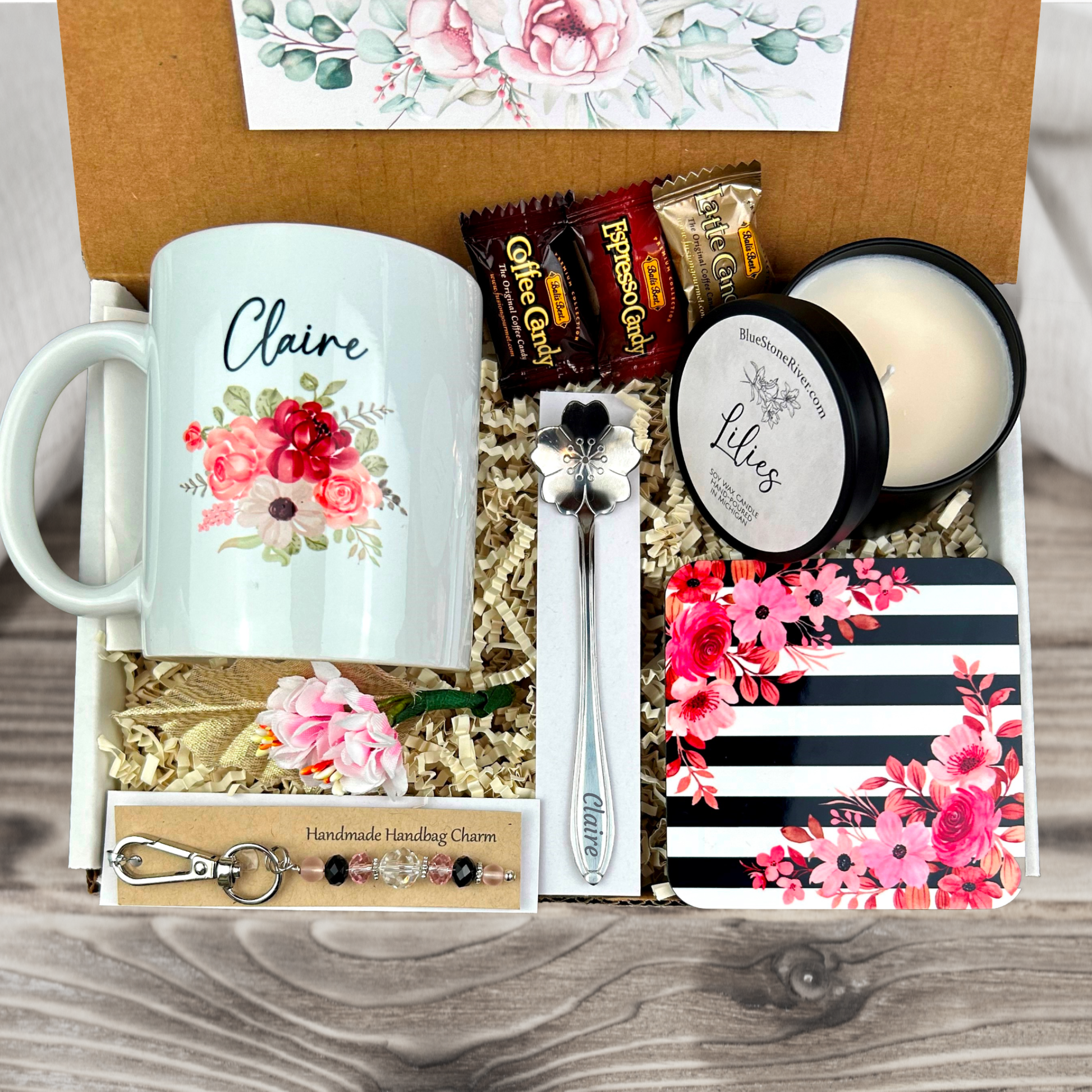  gift basket with a personalized pink coffee mug, engraved spoon, vibrant coaster, scented candle, artisan charm, and coffee treats for women’s present